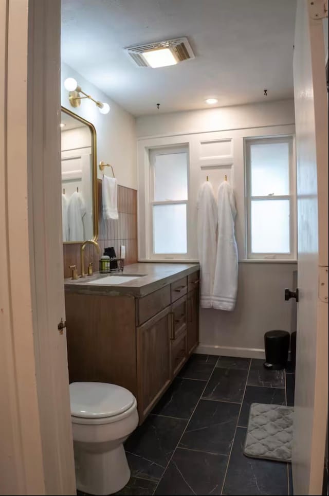 bathroom featuring vanity, decorative backsplash, and toilet