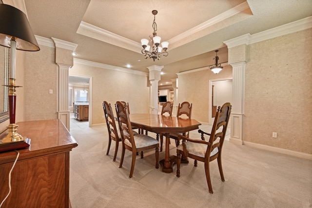 carpeted dining area with a tray ceiling, ornamental molding, and ornate columns