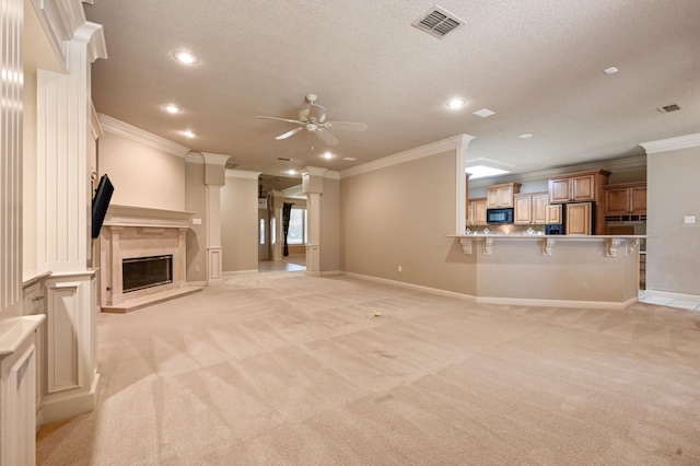 unfurnished living room featuring ornamental molding, light colored carpet, ceiling fan, and a fireplace