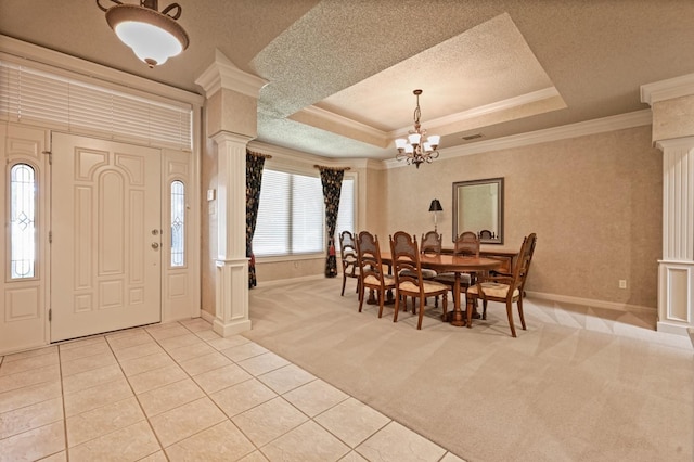 carpeted dining room with a raised ceiling, crown molding, and decorative columns