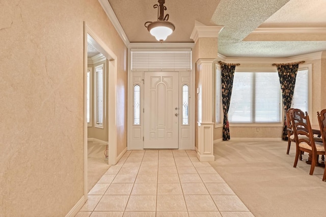 entrance foyer with light carpet, ornamental molding, and ornate columns