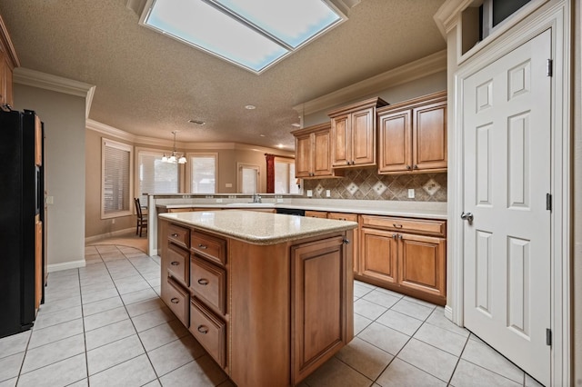 kitchen with black refrigerator, pendant lighting, decorative backsplash, ornamental molding, and light tile patterned floors