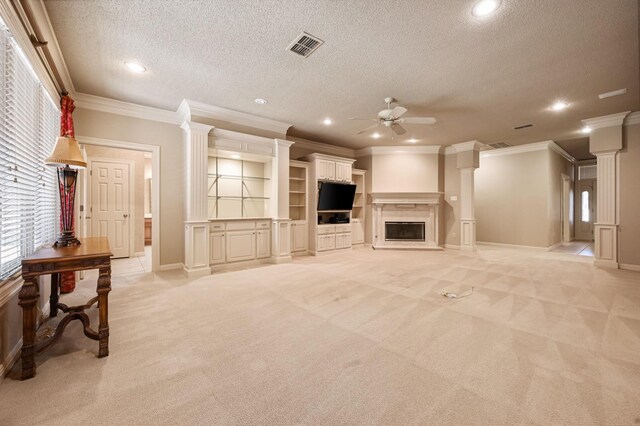 carpeted living room featuring ceiling fan, crown molding, a textured ceiling, and ornate columns