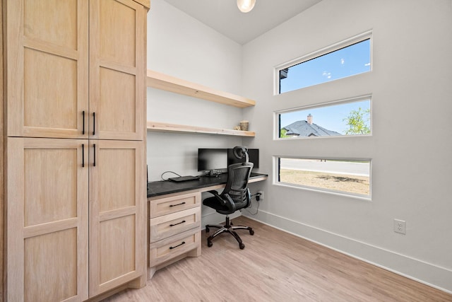 office space featuring light wood-style flooring, baseboards, a wealth of natural light, and built in study area
