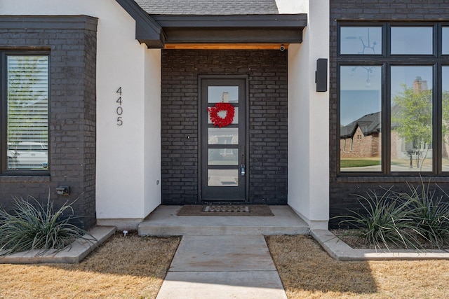 view of exterior entry featuring stucco siding and brick siding