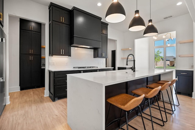 kitchen featuring light wood-style flooring, open shelves, a sink, and light countertops