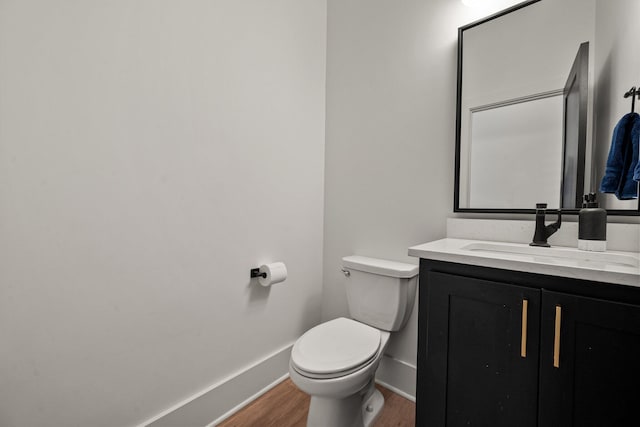 bathroom featuring baseboards, wood finished floors, vanity, and toilet