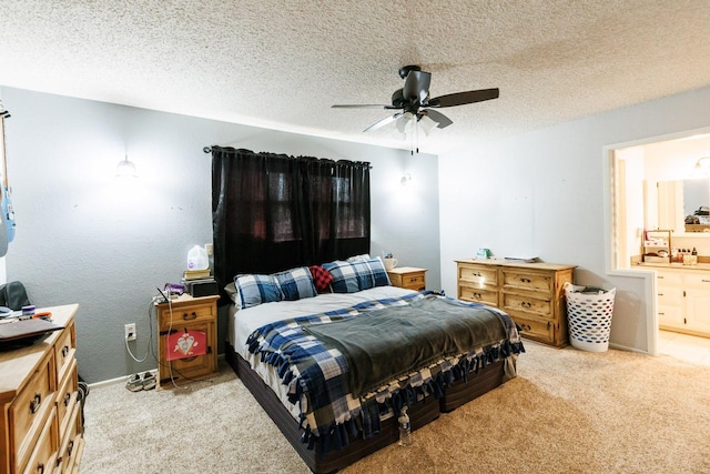 bedroom featuring ceiling fan, light carpet, a textured ceiling, and ensuite bath