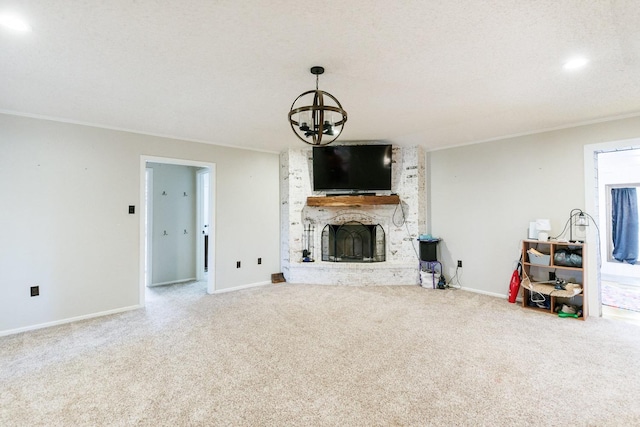 carpeted living room featuring a brick fireplace, a textured ceiling, ornamental molding, and a chandelier