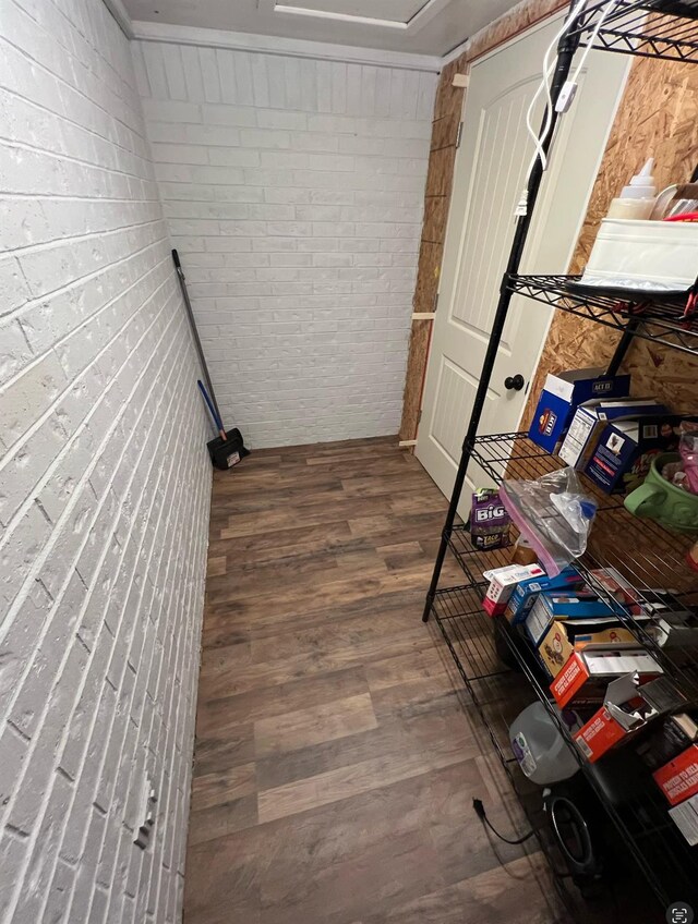 interior space featuring wood-type flooring and brick wall