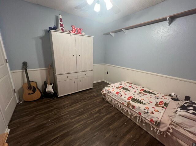 bedroom featuring ceiling fan, dark hardwood / wood-style floors, and a textured ceiling