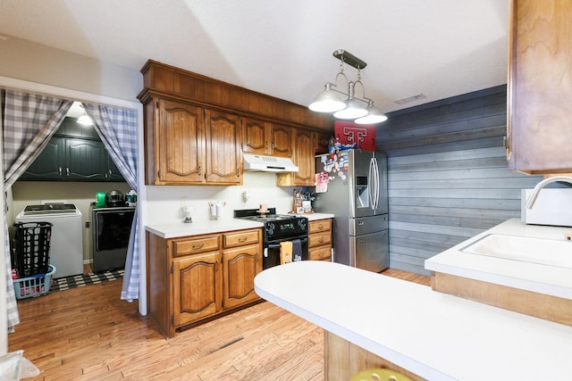 kitchen with pendant lighting, independent washer and dryer, light hardwood / wood-style floors, black stove, and stainless steel fridge with ice dispenser