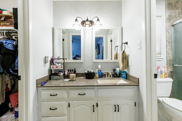 bathroom with vanity, toilet, and a shower with door