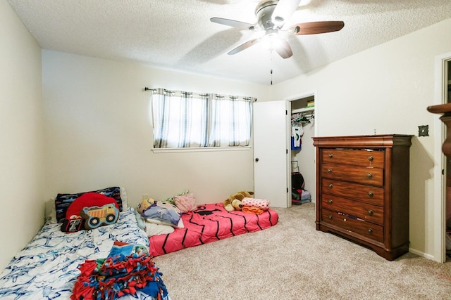 carpeted bedroom featuring ceiling fan, a spacious closet, and a textured ceiling