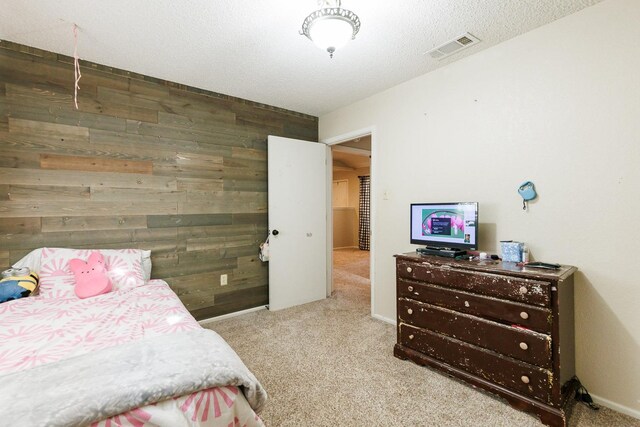 carpeted bedroom featuring a textured ceiling and wood walls