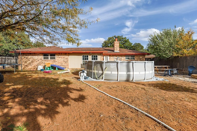 rear view of house featuring a fenced in pool and a trampoline