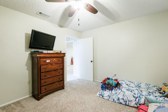 carpeted bedroom featuring ceiling fan and a textured ceiling