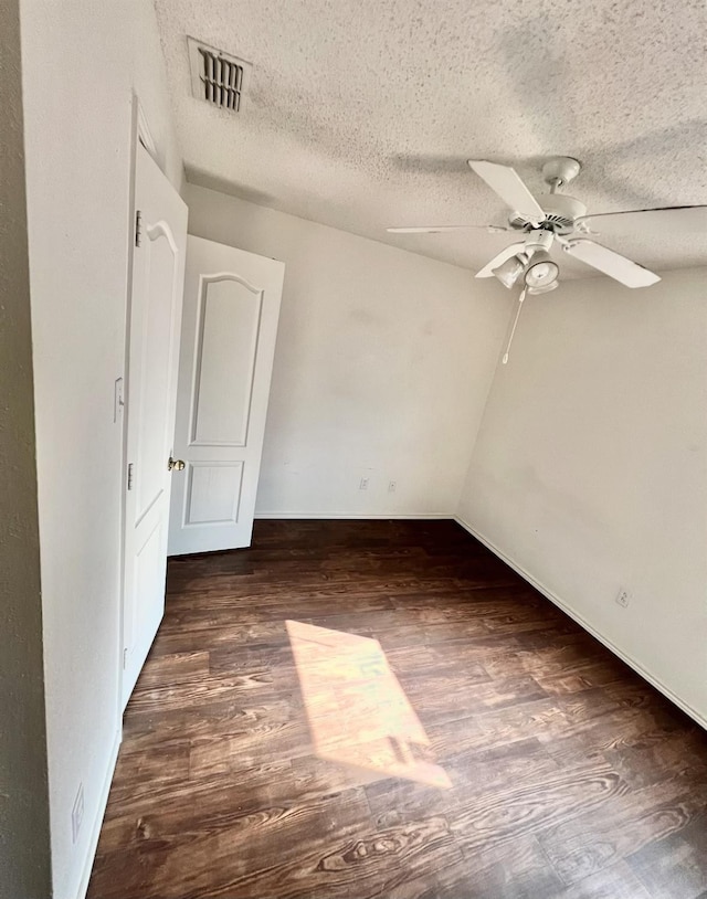 spare room featuring dark hardwood / wood-style flooring, ceiling fan, and a textured ceiling