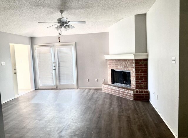 unfurnished living room with ceiling fan, dark hardwood / wood-style flooring, a textured ceiling, and a fireplace