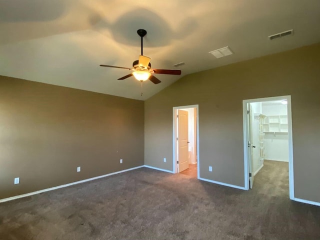 unfurnished bedroom featuring dark colored carpet, a spacious closet, vaulted ceiling, a closet, and ceiling fan