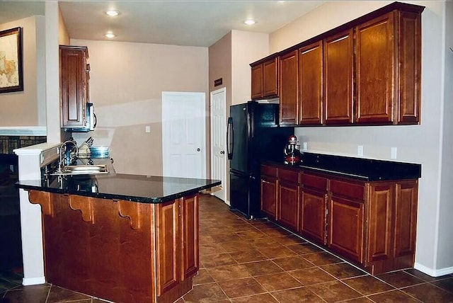 kitchen with black refrigerator, a breakfast bar, kitchen peninsula, and sink