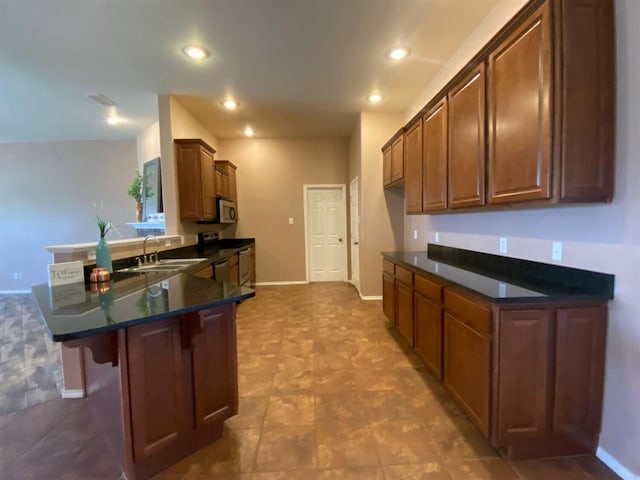 kitchen with appliances with stainless steel finishes, a kitchen breakfast bar, kitchen peninsula, and sink