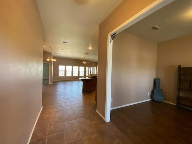 hall featuring an inviting chandelier and dark tile patterned floors