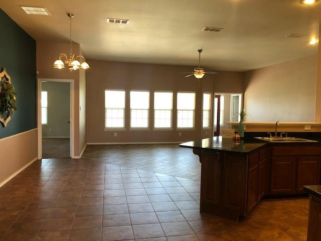 kitchen featuring ceiling fan with notable chandelier, sink, a center island with sink, and dark tile patterned floors