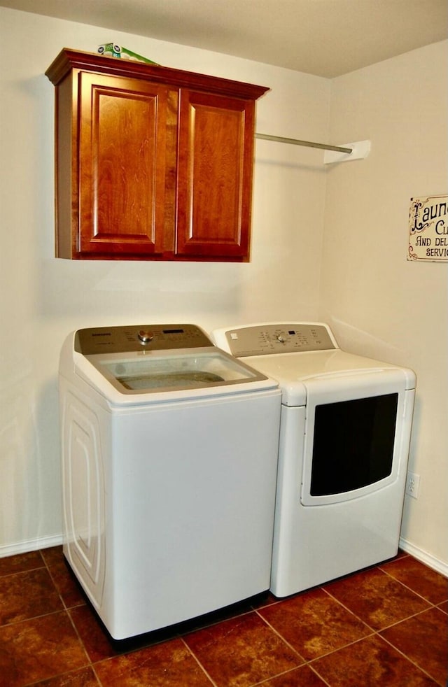 washroom with cabinets, washer and dryer, and dark tile patterned floors