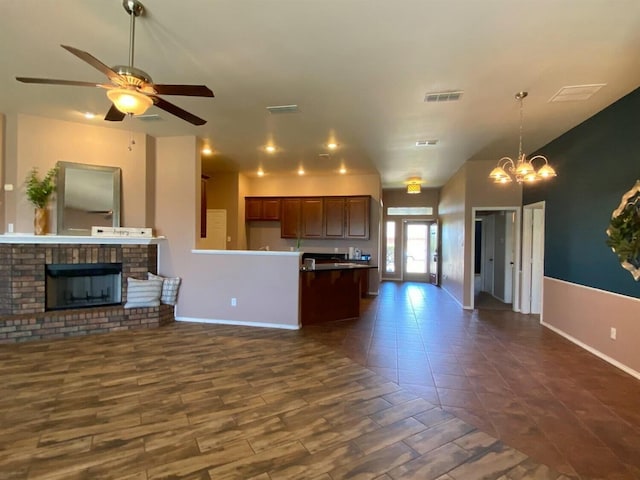 kitchen with dark hardwood / wood-style floors, ceiling fan with notable chandelier, and a fireplace