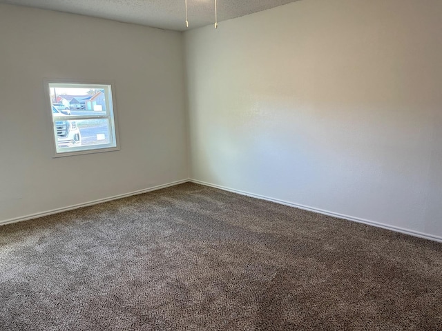 unfurnished room with dark colored carpet and a textured ceiling