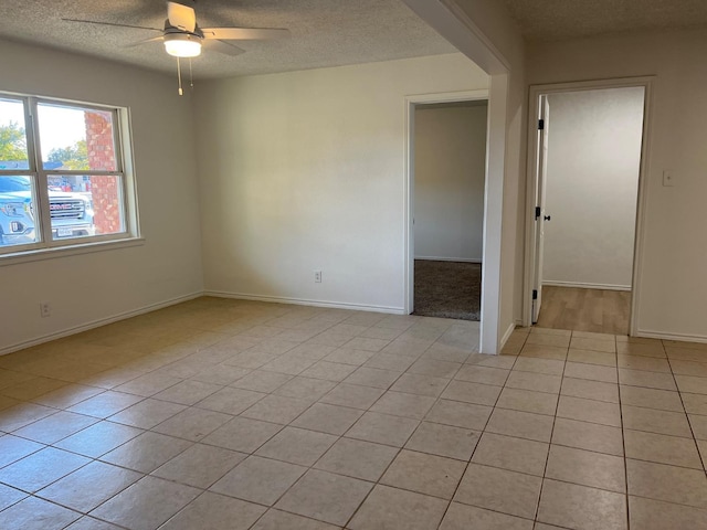 tiled empty room with ceiling fan and a textured ceiling