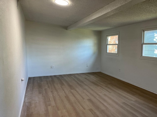 unfurnished room featuring hardwood / wood-style flooring, a textured ceiling, and beam ceiling