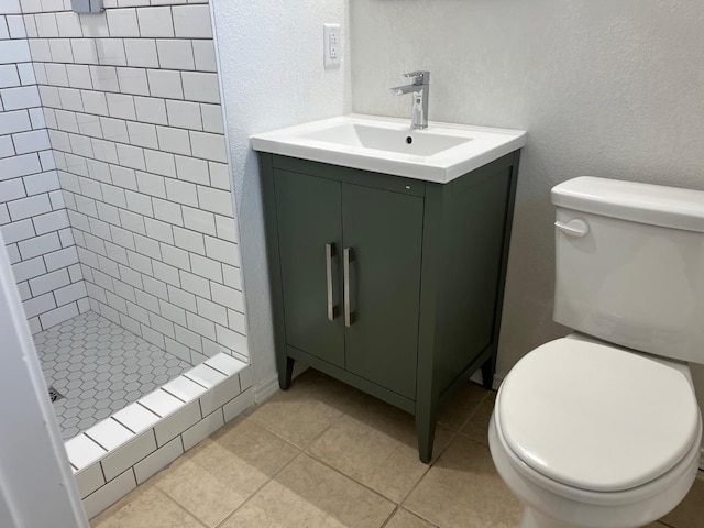 bathroom featuring tiled shower, vanity, toilet, and tile patterned floors