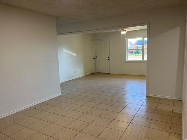 spare room featuring ceiling fan, light tile patterned floors, and a textured ceiling