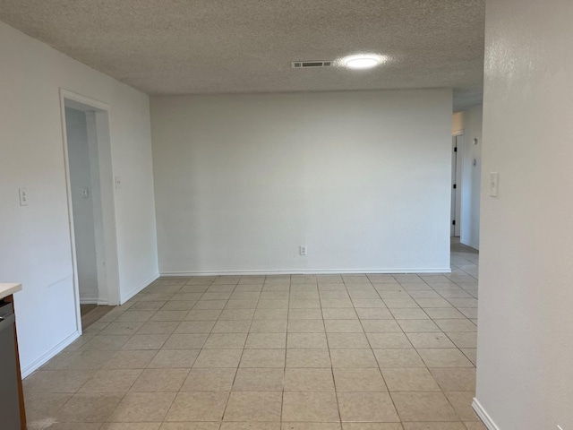 tiled empty room with a textured ceiling