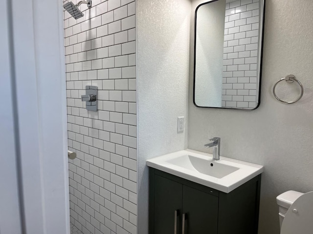 bathroom with vanity, toilet, and a tile shower