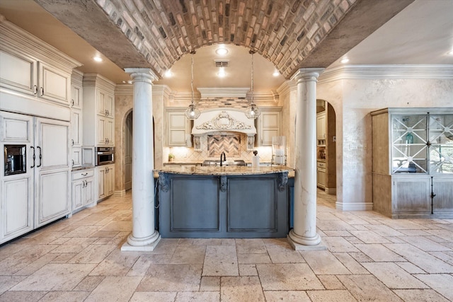 kitchen featuring brick ceiling, arched walkways, ornate columns, and stone tile flooring