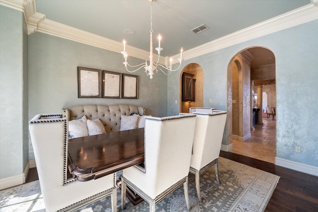 dining space with wood finished floors, visible vents, arched walkways, and ornamental molding