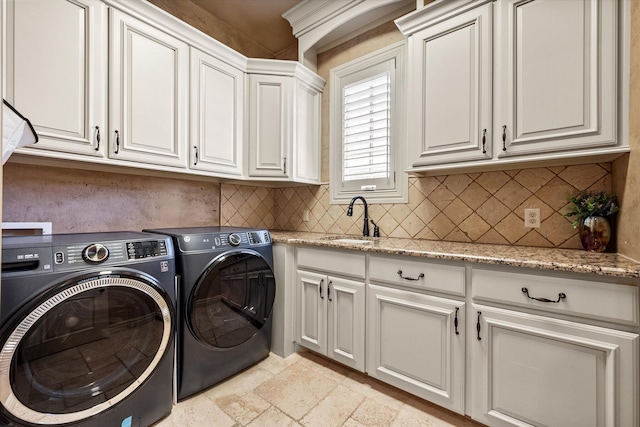 washroom with separate washer and dryer, cabinet space, stone tile flooring, and a sink