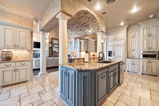 kitchen featuring stone tile floors, visible vents, ornate columns, oven, and a sink