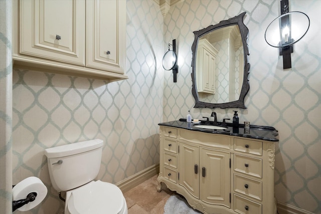 bathroom with baseboards, toilet, vanity, and wallpapered walls