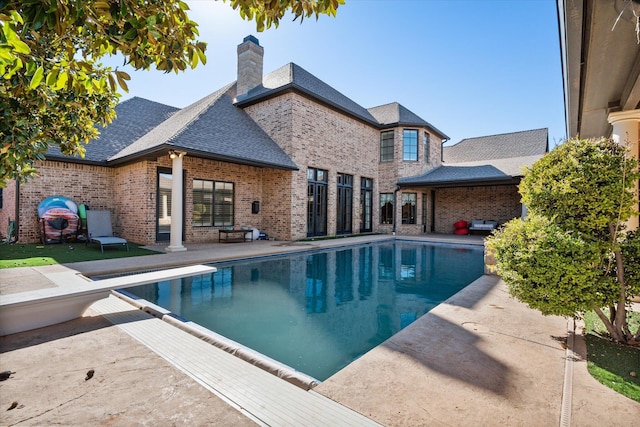 outdoor pool featuring a diving board and a patio