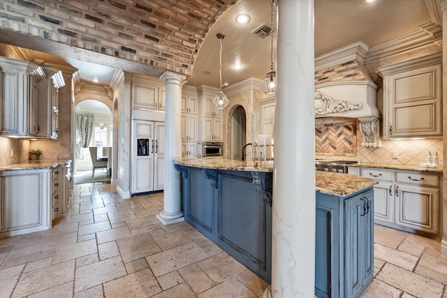 kitchen with stone tile floors, light stone counters, visible vents, arched walkways, and cream cabinetry