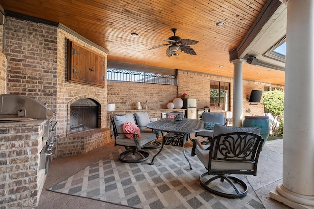 view of patio / terrace featuring ceiling fan, grilling area, exterior kitchen, and an outdoor brick fireplace