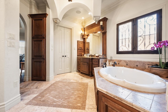 bathroom featuring vanity, a tub with jets, baseboards, and ornamental molding