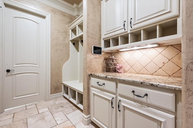 mudroom with crown molding and stone tile flooring