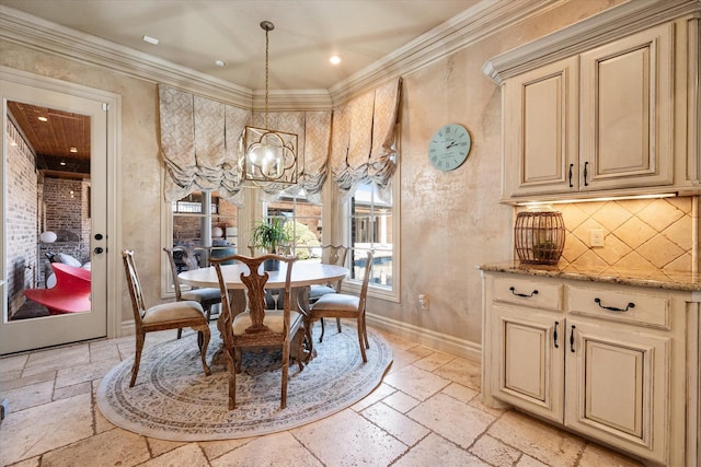 dining room with an inviting chandelier, crown molding, baseboards, and stone tile flooring