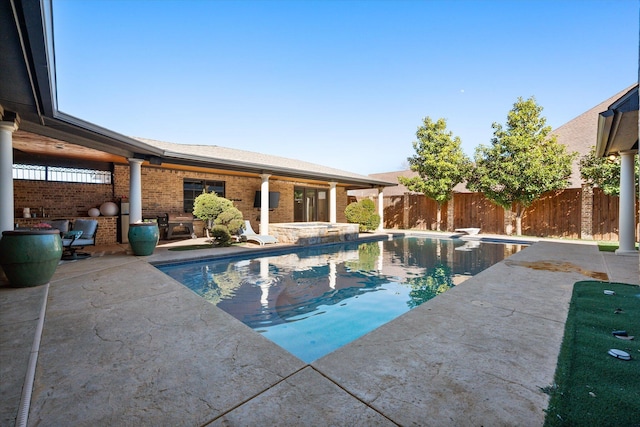 view of pool featuring a patio area, a pool with connected hot tub, and fence