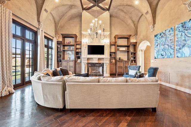 living area with baseboards, a fireplace, arched walkways, dark wood-style flooring, and a chandelier